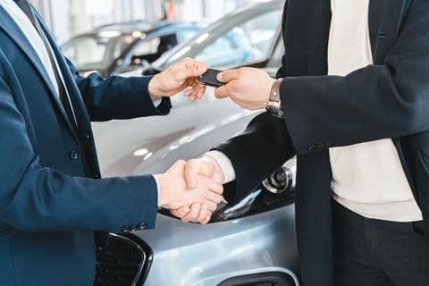 Two people shaking hands while exchanging keys